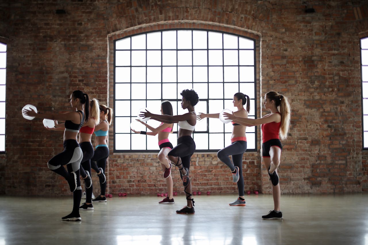 Women practicing yoga poses in a brick-walled studio, promoting fitness and flexibility.